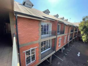 a red brick building with balconies and a parking lot at Executive suite@Lofts in Pretoria