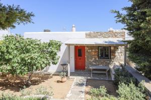 uma casa branca com uma porta vermelha e um banco em Elysium Paros Houses em Chrissi Akti