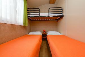 2 łóżka w małym pokoju z pomarańczową pościelą w obiekcie CAMP MRKVA MOBILE HOMES with POOL w Sukošanie +24 zdjęcia