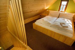 a bed in a wooden cabin with a window at Apartmány Severák Smrk in Janov nad Nisou