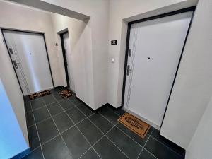 korytarz z 3 drzwiami i podłogą wyłożoną kafelkami w obiekcie Apartaments Baltycka 37 - Rzeszow w mieście Rzeszów