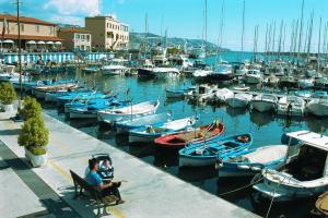 two people sitting in a chair at a marina with boats at Dolce Vita A 5 Minuti Dal Centro Con Parcheggio Privato Gratuito in Sanremo