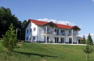 ein großes weißes Haus mit rotem Dach in der Unterkunft Hof am Horn - Fewos in der Natur in Laichingen