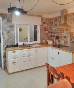 una cucina con armadi bianchi, tavolo e finestra di Casa Noray 18 a Playa Honda