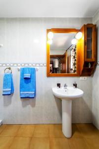 y baño con lavabo, espejo y toallas azules. en Casa Carmen, Montefrio, en Montefrío