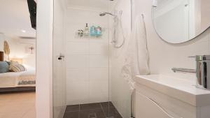 a white bathroom with a shower and a sink at MacMasters Studio Retreat in Macmasters Beach