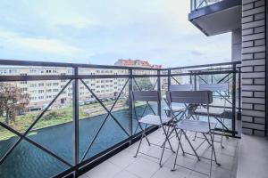 een balkon met 2 stoelen en uitzicht op een gebouw bij Platinium Dwie Motławy River View in Gdańsk