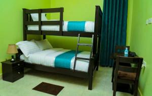 1 Schlafzimmer mit 2 Etagenbetten und einem Tisch in der Unterkunft Bwiranda Hotel in Kasese
