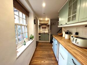 una cucina con armadi verdi e pavimenti in legno di Bath Road Holiday a Bradford on Avon