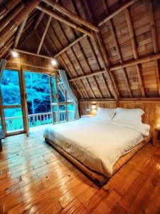 a bedroom with a large bed in a room with windows at Aksha Riverside Ubud in Tampaksiring
