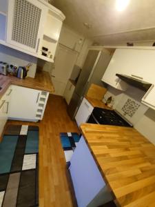 una pequeña cocina con armarios blancos y suelo de madera. en Edwardian 5 bedroom townhouse, next to underground, en Londres
