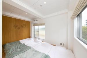 Ce lit se trouve dans un dortoir doté d'une grande fenêtre. dans l'établissement BANBOO HOUSE, à Osaka