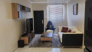ein Wohnzimmer mit einem Sofa und einem TV in der Unterkunft Chez Gabrielle in Lusaka