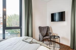 ein Schlafzimmer mit einem Stuhl und einem TV an der Wand in der Unterkunft Baker`s Home in Augsburg