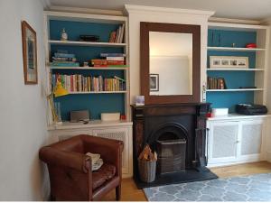 - un salon avec une chaise et une cheminée dans l'établissement Victorian Terraced House in Salisbury; 3 bedrooms, à Salisbury