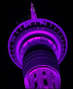 a tower lit up in purple at night at Skytower view and Seaview 2 bedroom Apartment in Auckland