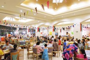 Eine Menschenmenge, die in einem Restaurant an Tischen sitzt. in der Unterkunft Thumrin Thana Hotel in Trang