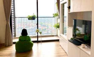 eine Person, die auf dem Boden in einem Wohnzimmer mit Blick aus dem Fenster sitzt in der Unterkunft Ecopark Happy Haven in HÆ°ng YÃªn