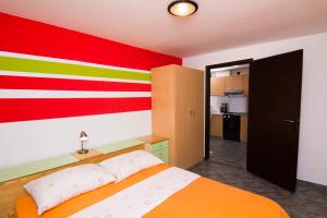 a bedroom with a bed with a colorful wall at Apartmani Žužić in Krk