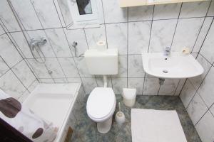 a white bathroom with a toilet and a sink at Apartmani Žužić in Krk +6 photos