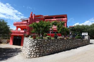 a red building with a stone wall in front of it at Apartmani Žužić in Krk