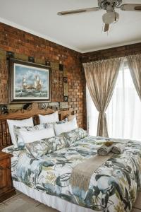 a bedroom with a large bed with a brick wall at MFT GUEST HOUSE in Boksburg