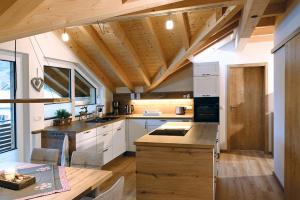 cocina con armarios blancos y techo de madera en Luginsland, en Sonthofen