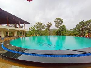 a large blue swimming pool in a building at STAYMAKER Sereno Resort in Sakleshpur
