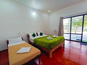 a bedroom with two beds and a large window at STAYMAKER Sereno Resort in Sakleshpur