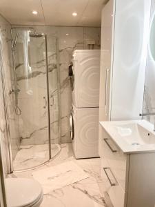 baño blanco con ducha y nevera. en Modern 2 bedroom apartment in Oslo city centre, en Oslo