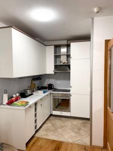 a kitchen with white cabinets and white counters at Maja Apartman Bjelasnica in Bjelašnica