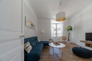 sala de estar con sofá azul y mesa en Le Louis - Appartement 2 chambres, proche du centre et lac, en Vichy