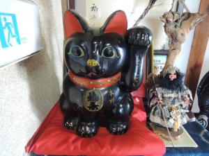 posąg czarnego kota siedzącego na czerwonej poduszce w obiekcie Honno Ryokan / Vacation STAY 60049 w mieście Yahaba