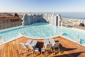 a pool on the roof of a building with chairs at Grand Hotel Principe Di Piemonte in Viareggio