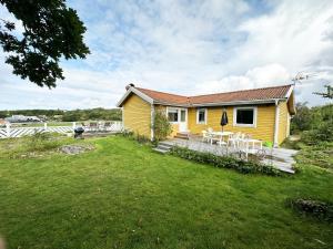 Cottage with sea view near Marstrand في Lycke: منزل أصفر مع طاولات وكراسي في ساحة