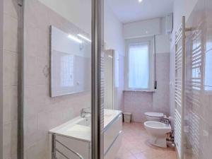 La salle de bains blanche est pourvue d'un lavabo et de toilettes. dans l'établissement Appartamento vicino al Porto, à Varazze