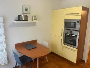 una pequeña cocina con mesa de madera y microondas en Maison plain-pied hyper centre ville Perros, en Perros-Guirec