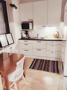 a kitchen with white cabinets and a wooden table at Studio Porin Karhu, home away home in Pori city center, free parking in Pori