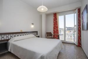 1 dormitorio con cama blanca y ventana grande en Hotel La Ruta, en Tapia de Casariego