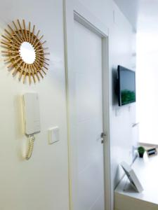 a bathroom with a phone and a mirror on the wall at H&H Suite El Mirlo in Granada