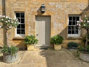 a brick building with a door and three potted plants at Escape to Ash House 18th Century Manor in Somerset in Martock