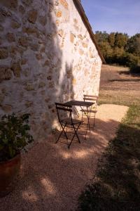 stół i krzesła siedzące obok kamiennej ściany w obiekcie Bessire Chambres & table d'hôtes 