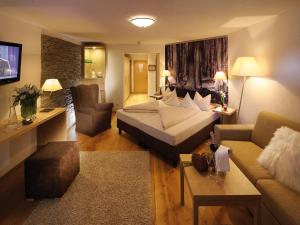 ein Hotelzimmer mit einem Bett und einem Wohnzimmer in der Unterkunft Boutique Hotel Haidachhof superior in Fügen