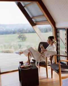 une femme assise sur une chaise avec un verre de vin dans l'établissement Kimo Estate, à Gundagai