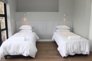 2 bedden in een kamer met witte lakens en kussens bij Golf Lodge at Pearl Valley Golf Estate Spa in Simondium
