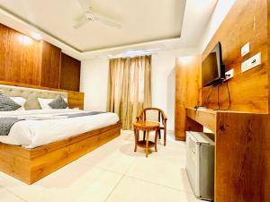 Hotel The Glory Near Delhi International Airport في نيودلهي: غرفة نوم فيها سرير وتلفزيون