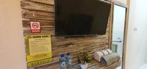 TV de pantalla plana en una pared de madera con botellas de agua en Ana homestay en Negara