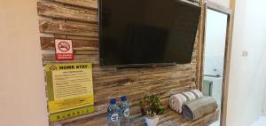 a flat screen tv on a wooden wall with bottles of water at Ana homestay in Negara