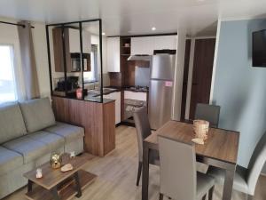a kitchen and living room with a table and a couch at Ô Coeur d'Eden ,2 mobilhomes l'Ôriginal et le BÔ'Aime in Piriac-sur-Mer