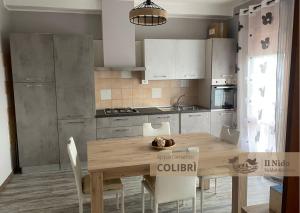 cocina con mesa de madera y armarios blancos en IL NIDO Appartamenti Turistici, en Valdobbiadene